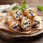 Close-up shot of a single cannoli cut in half showing creamy ricotta filling with chocolate chips