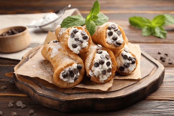 Close-up shot of a single cannoli cut in half showing creamy ricotta filling with chocolate chips