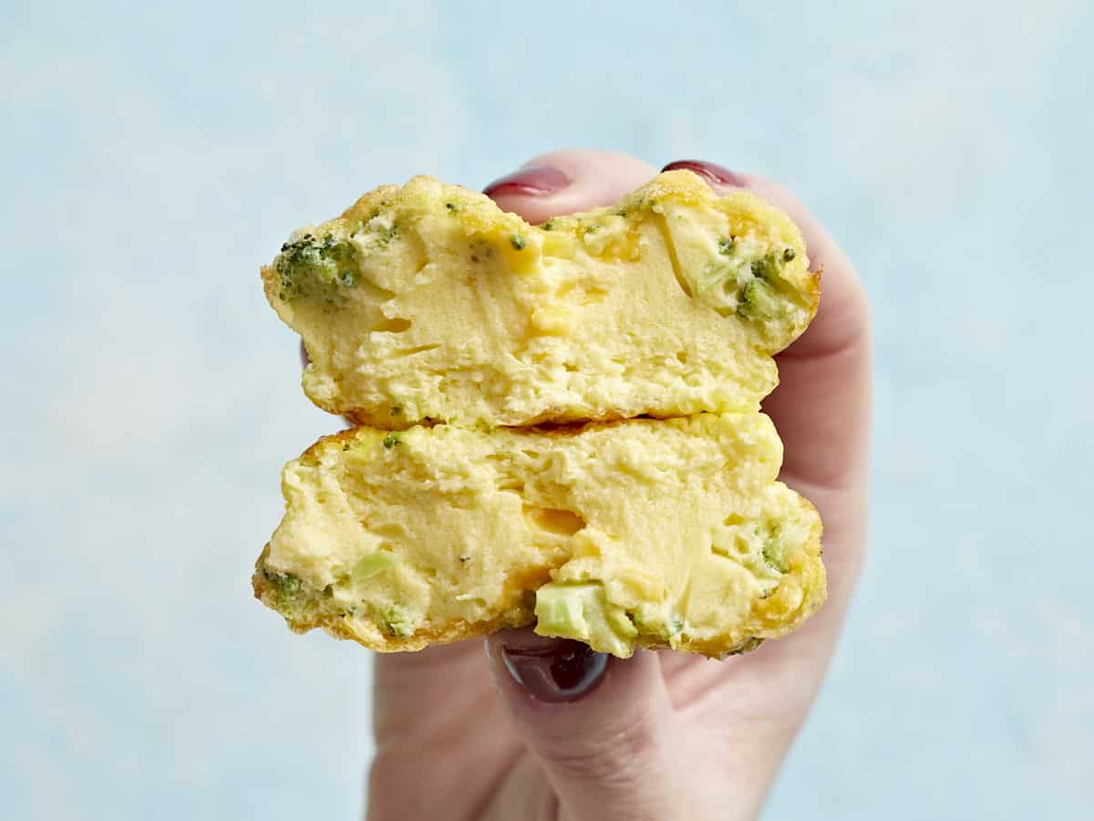 Close-up shot of a halved egg bite showing the creamy, fluffy interior texture with visible herbs and vegetables
