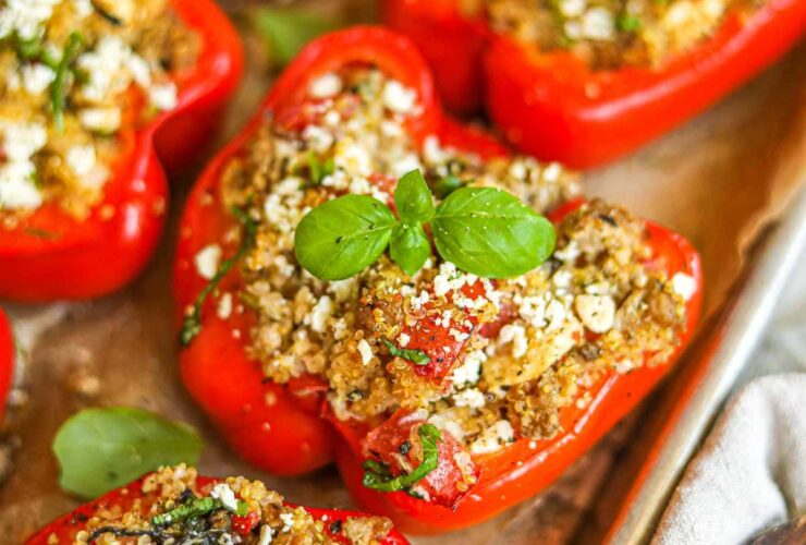 Colorful stuffed bell pepper boats filled with ground turkey and quinoa, garnished with fresh parsley and feta, served on a white platter with Mediterranean herbs