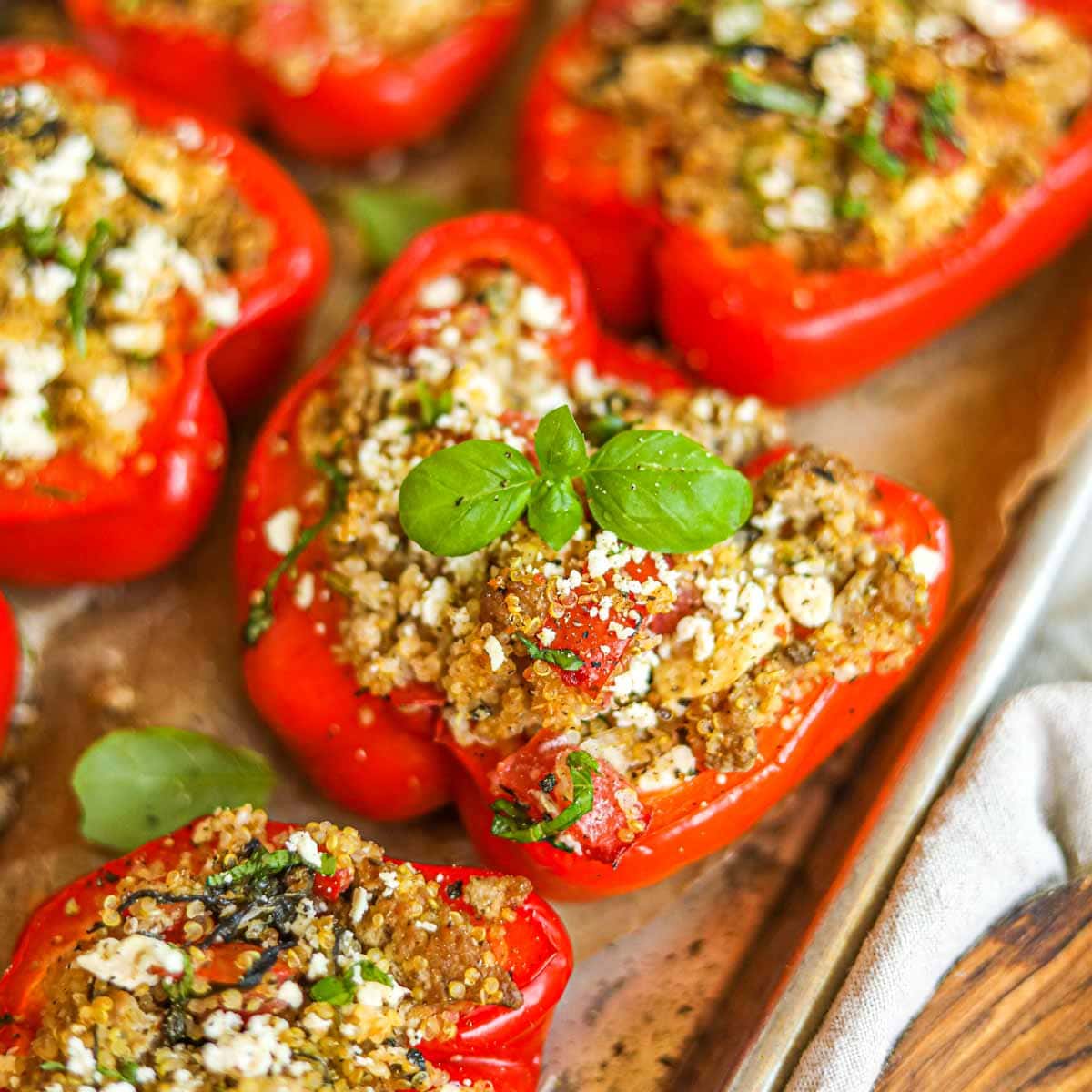 Colorful stuffed bell pepper boats filled with ground turkey and quinoa, garnished with fresh parsley and feta, served on a white platter with Mediterranean herbs