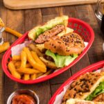 Bacon Ranch Burgers stacked high on a toasted brioche bun with crispy bacon, lettuce, and tomato on a wooden serving board
