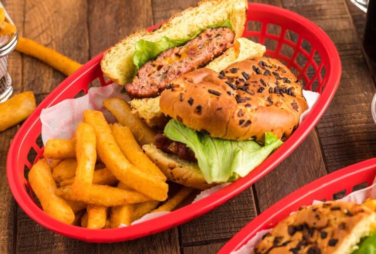 Bacon Ranch Burgers stacked high on a toasted brioche bun with crispy bacon, lettuce, and tomato on a wooden serving board
