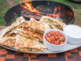 Campfire Quesadillas — Crispy 2-Ingredient Skillet Magic You'll Make All Summer 36 Golden crispy campfire quesadillas served on a rustic wooden board outdoors near a campfire, cut into wedges with melted cheese pulling apart