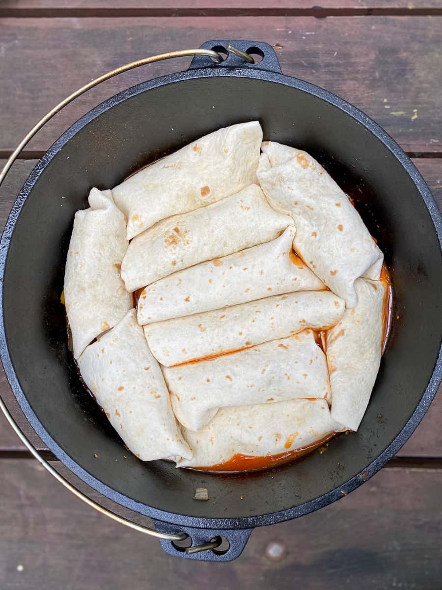 Campfire Quesadillas — Crispy 2-Ingredient Skillet Magic You'll Make All Summer 27 Step-by-step shot showing a flour tortilla being pressed in a cast iron skillet over a campfire with melted cheese visible inside