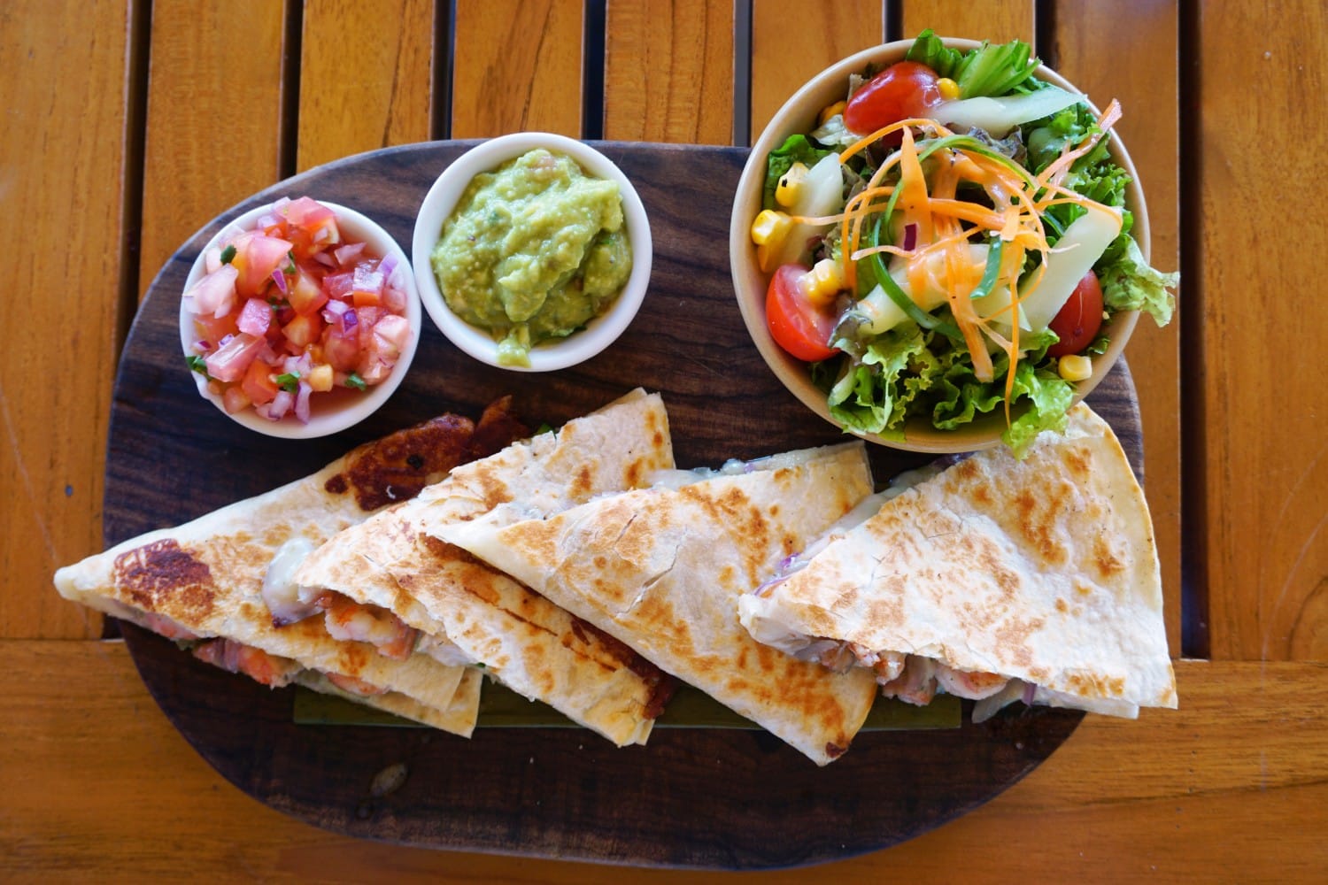 Campfire Quesadillas — Crispy 2-Ingredient Skillet Magic You'll Make All Summer 28 Close-up of campfire quesadilla wedges stacked on a rustic plate with a cheese pull, served with fresh salsa and guacamole outdoors