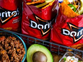 Campfire Walking Tacos — Easy Dorito Bag Tacos with Seasoned Beef & All the Toppings 36 Campfire walking tacos served in open Dorito bags with seasoned beef, shredded cheese, sour cream, salsa, and fresh toppings on a rustic wooden camp table beside a glowing campfire at dusk