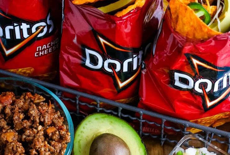 Campfire Walking Tacos — Easy Dorito Bag Tacos with Seasoned Beef & All the Toppings 33 Campfire walking tacos served in open Dorito bags with seasoned beef, shredded cheese, sour cream, salsa, and fresh toppings on a rustic wooden camp table beside a glowing campfire at dusk