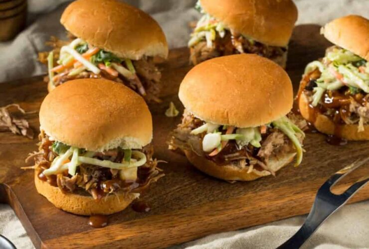 Instant Pot Pulled Pork for Camping — Make-Ahead Sliders from the Cooler 27 Instant pot pulled pork for camping served on slider buns with coleslaw on a wooden picnic table outdoors, golden hour light