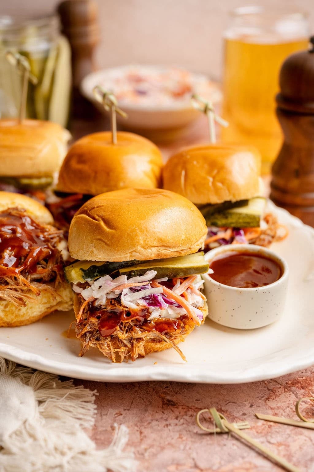 Instant Pot Pulled Pork for Camping — Make-Ahead Sliders from the Cooler 28 Close-up of pulled pork sliders stacked on a wooden board at a campsite, topped with coleslaw and pickles, with a camp lantern softly lit in the background