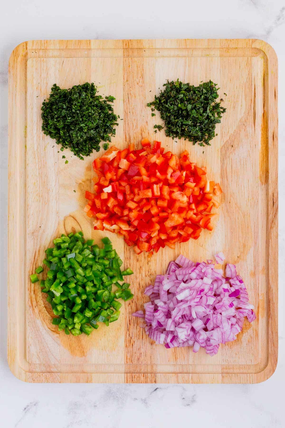 Diced peaches, mango, jalapeño, red onion, and cilantro arranged in separate small bowls on a wooden cutting board with a knife and lime halves beside them
