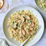 Beef Stroganoff served in a wide bowl over egg noodles, garnished with fresh parsley, rich creamy mushroom sauce visible