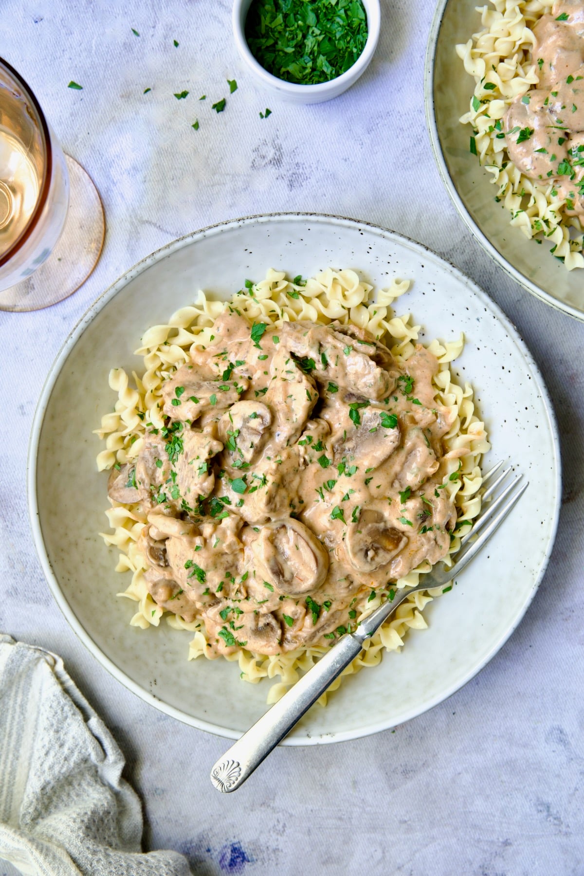 Beef Stroganoff served in a wide bowl over egg noodles, garnished with fresh parsley, rich creamy mushroom sauce visible