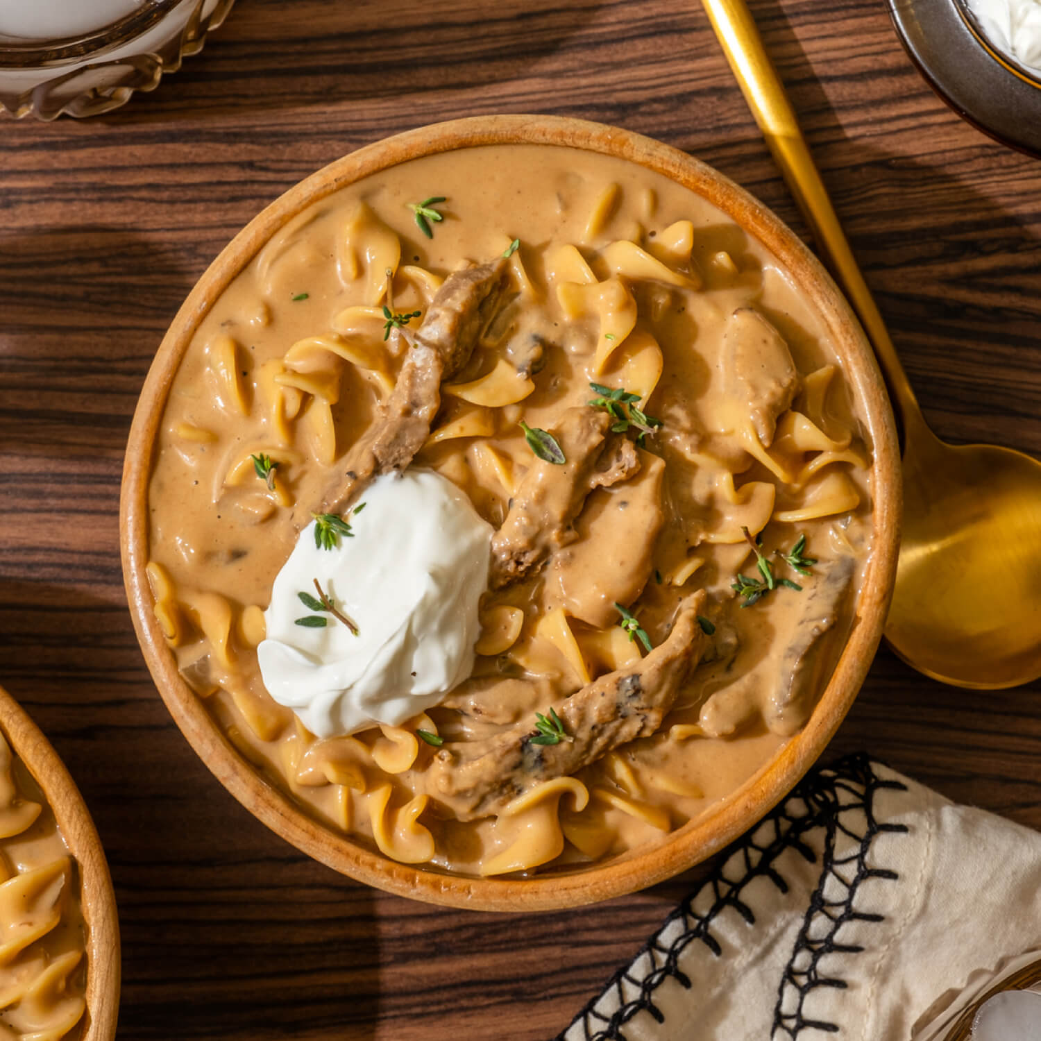 Close-up of creamy Beef Stroganoff sauce coating egg noodles, with golden mushrooms and tender beef strips visible, served in a rustic bowl