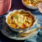 A steaming bowl of homemade chicken and dumplings with fluffy dumplings and tender shredded chicken in a rich golden broth, garnished with fresh parsley