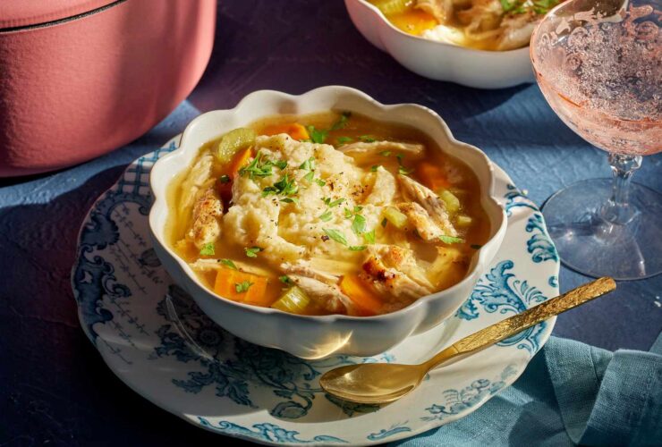 A steaming bowl of homemade chicken and dumplings with fluffy dumplings and tender shredded chicken in a rich golden broth, garnished with fresh parsley