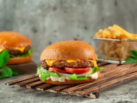 Classic Cheeseburgers — The All-American Backyard Burger Done Right 34 Classic Cheeseburgers stacked high with melted American cheese, crisp lettuce, tomato, and pickles on a toasted brioche bun, served on a wooden board at a sunny backyard cookout