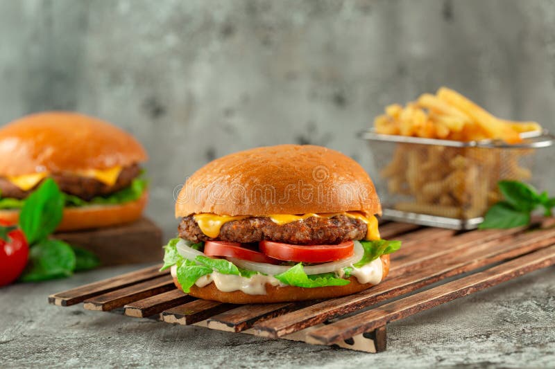 Classic Cheeseburgers — The All-American Backyard Burger Done Right 26 Classic Cheeseburgers stacked high with melted American cheese, crisp lettuce, tomato, and pickles on a toasted brioche bun, served on a wooden board at a sunny backyard cookout