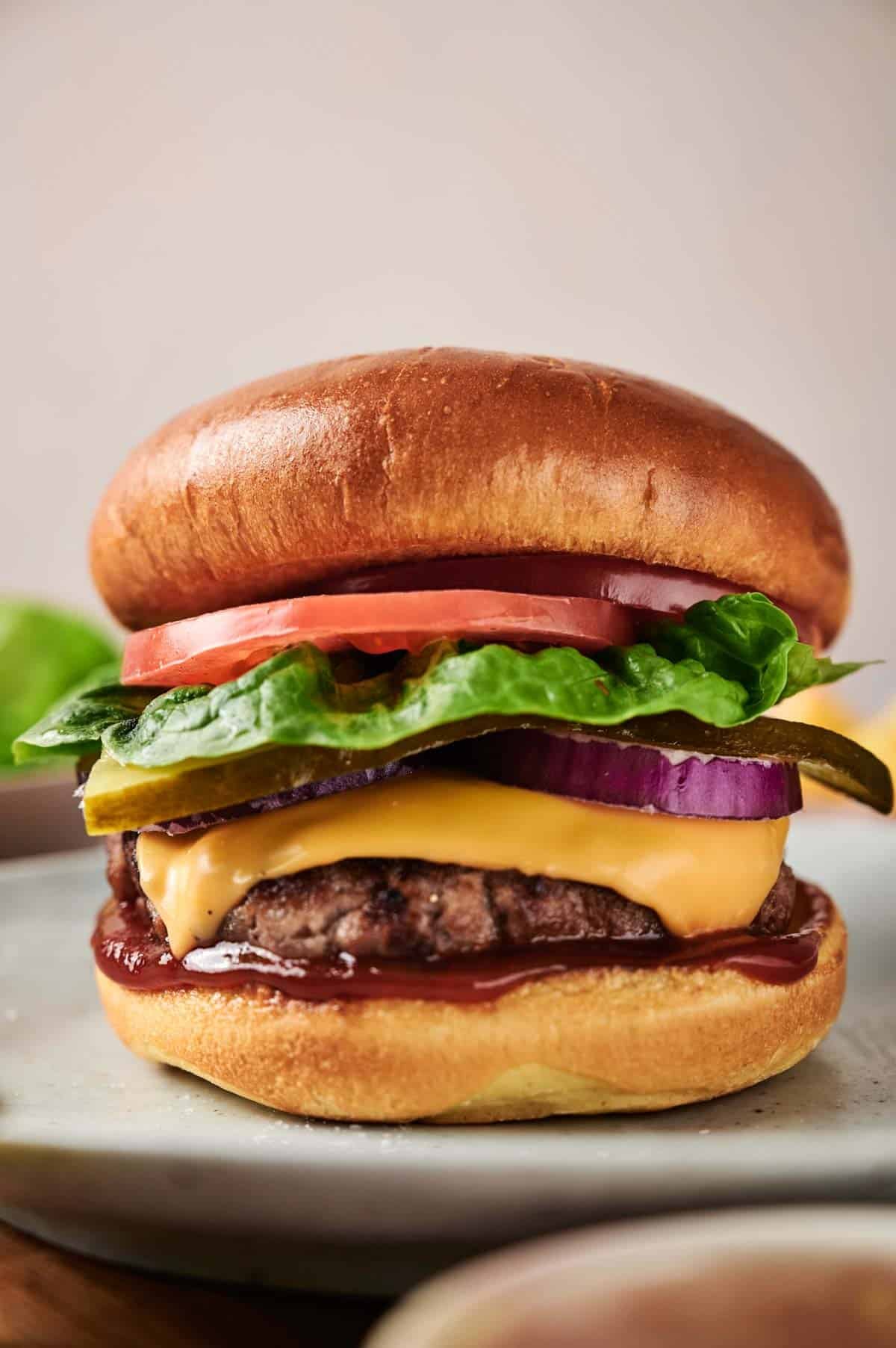 Classic Cheeseburgers — The All-American Backyard Burger Done Right 27 Ingredients for Classic Cheeseburgers laid out flat on a white marble surface — ground beef patties, cheese slices, tomato, lettuce, pickles, brioche buns, and condiments