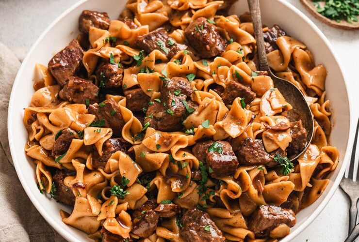 Crockpot Beef and Noodles served in a wide bowl with tender shredded beef over egg noodles in rich brown gravy, garnished with fresh parsley