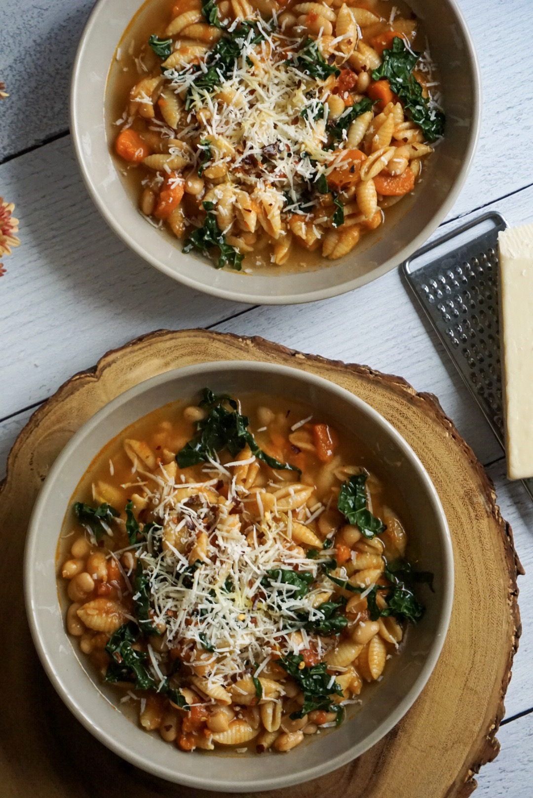 Close-up of a rustic ceramic bowl of Crockpot Pasta e Fagioli, showing the thick tomato broth, plump cannellini beans, ground beef, and ditalini pasta, topped with freshly grated Parmesan and a drizzle of olive oil, steam rising gently