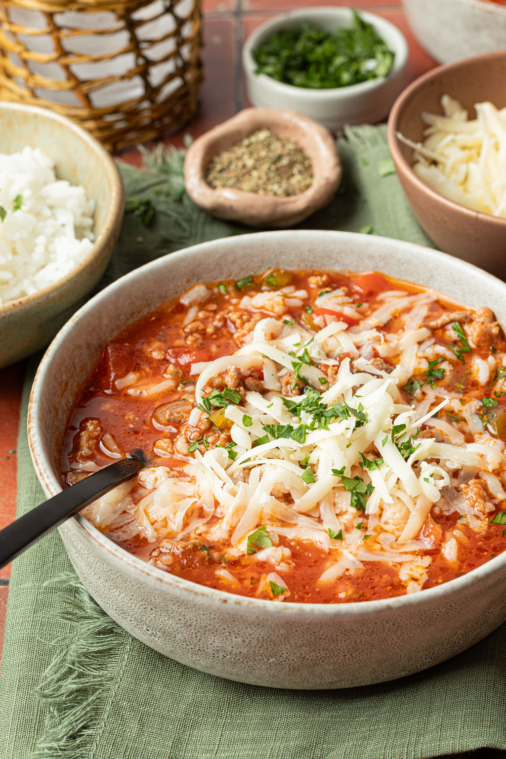 Crockpot Stuffed Pepper Soup — All the Comfort of Stuffed Peppers in One Easy Bowl 26 A rustic white bowl filled with Crockpot Stuffed Pepper Soup topped with shredded cheese and fresh parsley, set on a wooden table with a slow cooker in the background