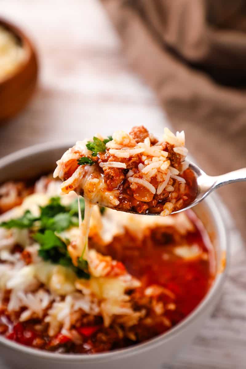 Crockpot Stuffed Pepper Soup — All the Comfort of Stuffed Peppers in One Easy Bowl 28 A close-up shot of a ladle lifting a scoop of Crockpot Stuffed Pepper Soup from a slow cooker, showing colorful bell pepper pieces, rice, and ground beef in a rich red tomato broth