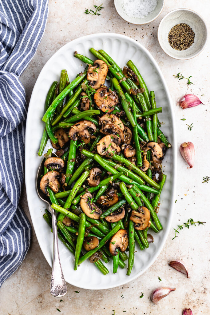 Green Bean Casserole — The Classic Comfort Dish Made Cleaner & Better 27 Overhead shot of ingredients for green bean casserole laid out on a marble surface — fresh green beans, cremini mushrooms, garlic, shallots, broth, and a small bowl of flour
