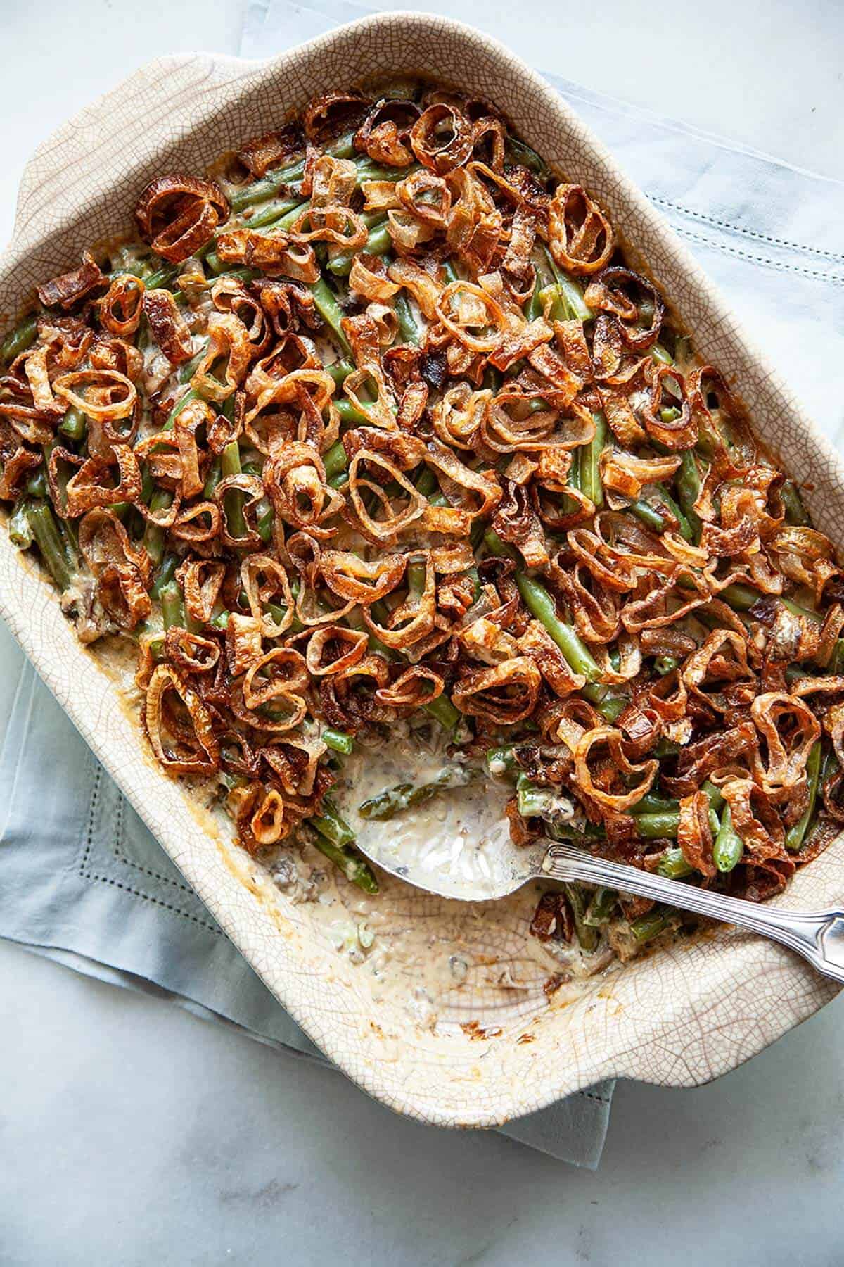 Green Bean Casserole — The Classic Comfort Dish Made Cleaner & Better 28 Close-up of a serving spoon lifting a generous scoop of green bean casserole from the dish, showing the creamy mushroom sauce and golden crispy shallot topping in beautiful detail