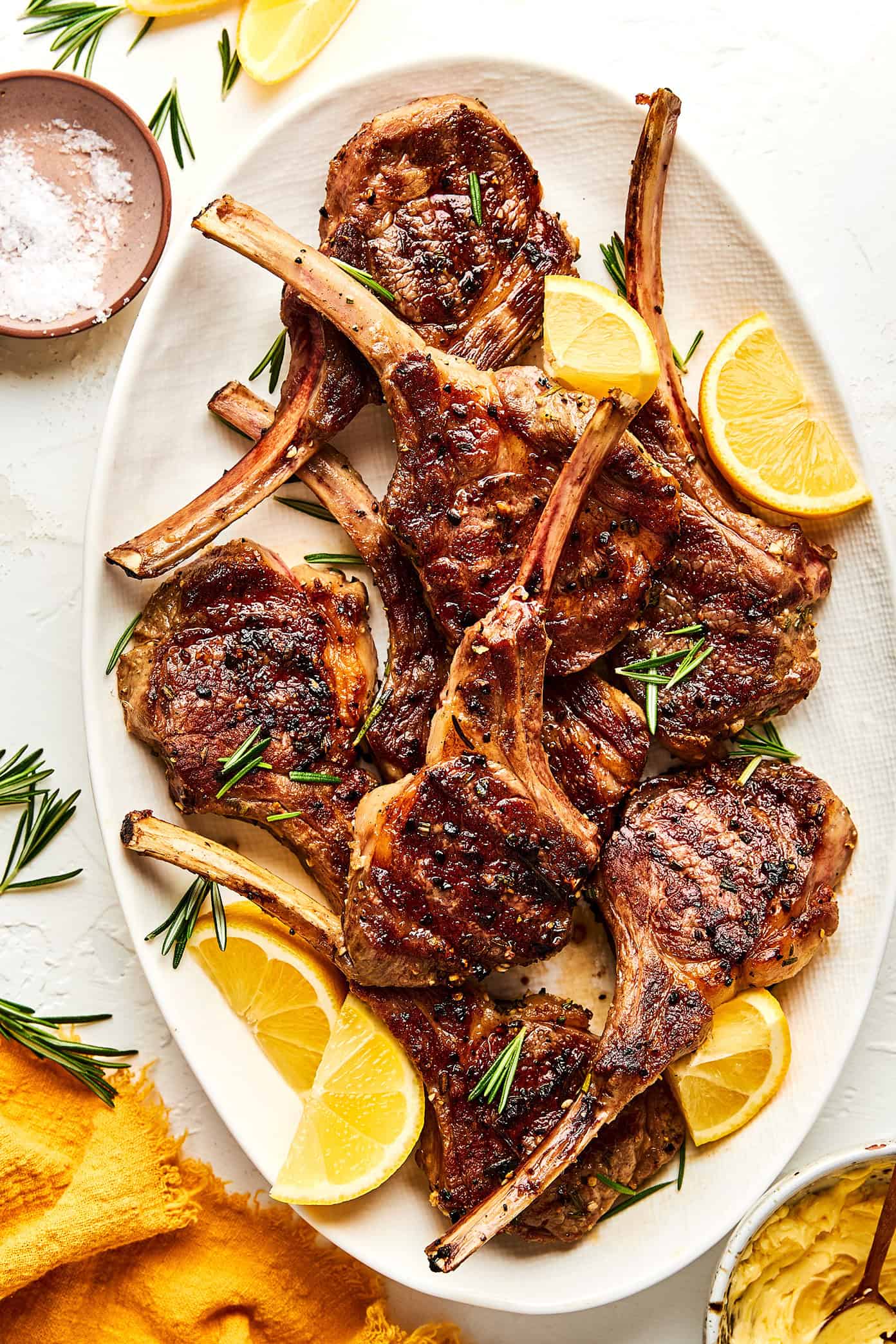 beautifully plated grilled lamb chops with rosemary garlic herb crust on a wooden board with lemon wedges and fresh herbs