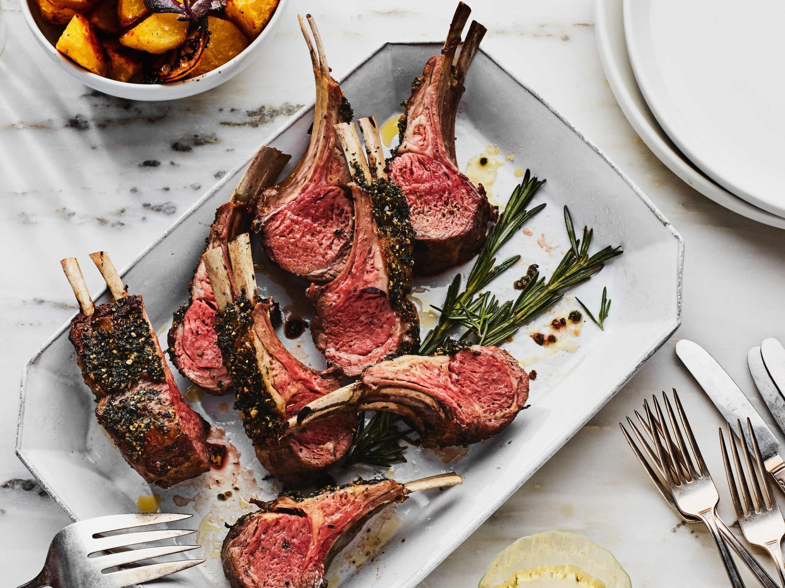 close-up of grilled lamb chops sliced to reveal rosy medium-rare interior with herb crust and lemon wedge garnish on a rustic plate