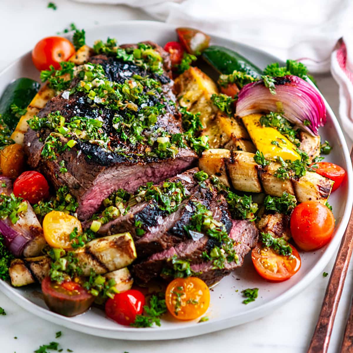 Close-up of thinly sliced grilled tri-tip fanned out on a plate, showing the pink interior and smoky crust, garnished with fresh parsley and served with roasted vegetables