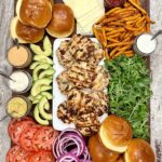 Juicy turkey burgers stacked on a toasted brioche bun with lettuce, tomato, and avocado, served on a wooden board with a side of sweet potato fries