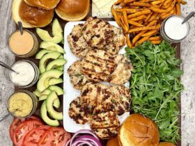 Juicy turkey burgers stacked on a toasted brioche bun with lettuce, tomato, and avocado, served on a wooden board with a side of sweet potato fries
