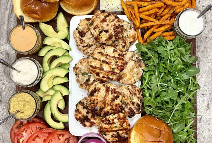 Juicy turkey burgers stacked on a toasted brioche bun with lettuce, tomato, and avocado, served on a wooden board with a side of sweet potato fries