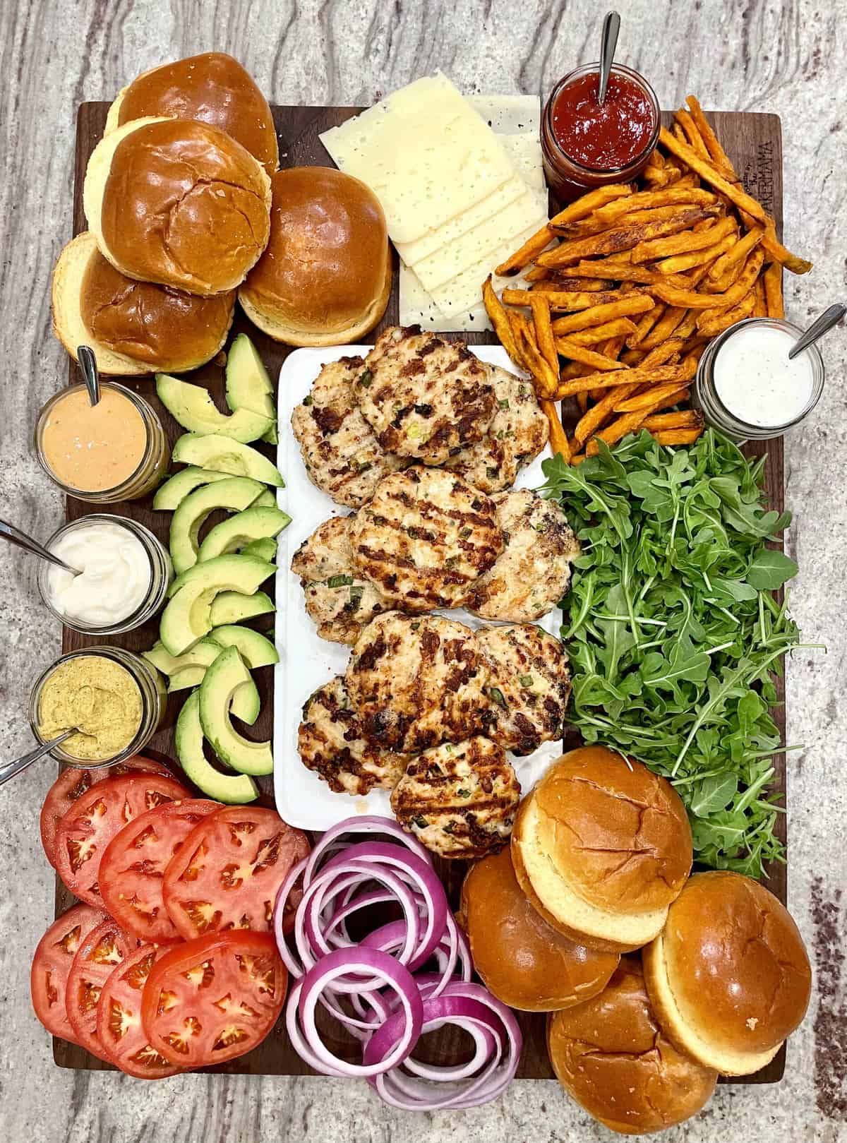 Juicy turkey burgers stacked on a toasted brioche bun with lettuce, tomato, and avocado, served on a wooden board with a side of sweet potato fries