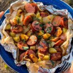 Kielbasa and potato foil packets opened on a plate showing golden sausage slices and tender potatoes with a glossy mustard glaze, garnished with fresh parsley