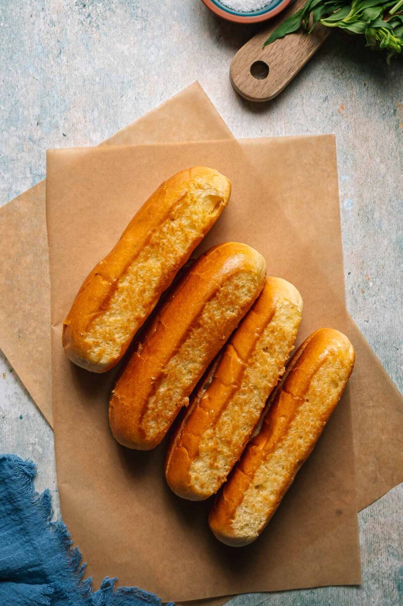 Classic Maine Lobster Rolls served on buttered toasted split-top buns with fresh chives and lemon wedges on a wooden board by the ocean