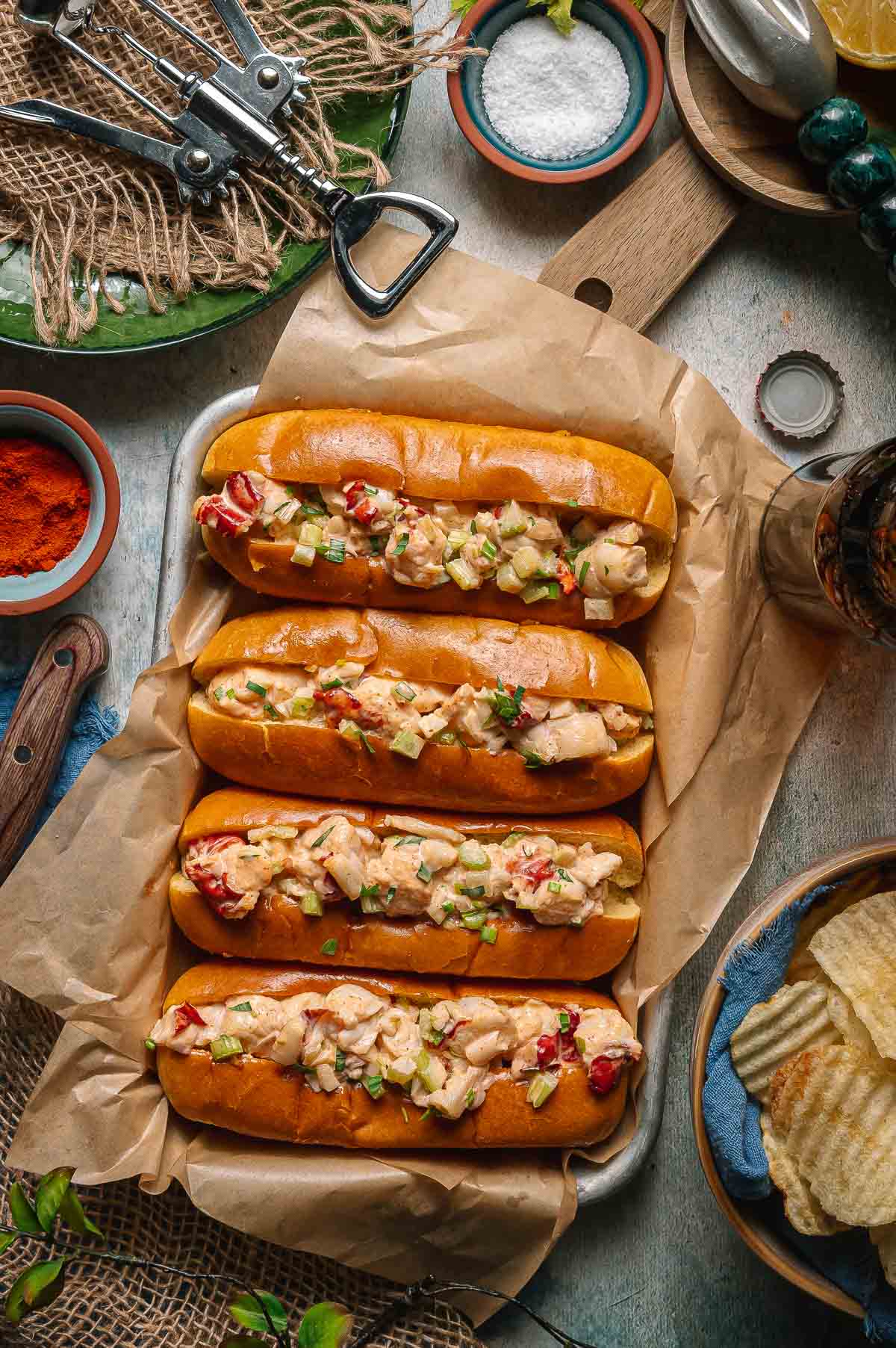 Close-up of Maine Lobster Roll overflowing with chunky lobster meat on a golden buttered toasted bun with chives and a lemon wedge on a sunny summer table