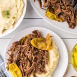 Mississippi Pot Roast served on a white platter with shredded beef, pepperoncini peppers, and rich golden gravy, garnished with fresh parsley