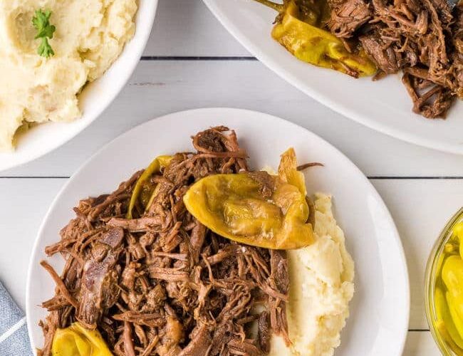 Mississippi Pot Roast served on a white platter with shredded beef, pepperoncini peppers, and rich golden gravy, garnished with fresh parsley