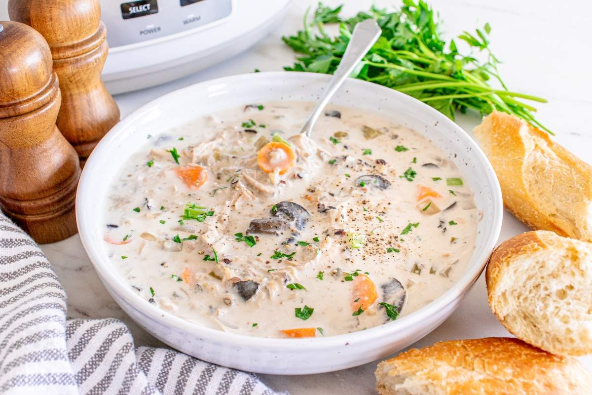 Slow Cooker Chicken Wild Rice Soup — Creamy Minnesota-Style Comfort in a Bowl 26 Slow cooker chicken wild rice soup served in a rustic white ceramic bowl, garnished with fresh thyme and cracked black pepper, steam rising, set on a warm wooden table with a linen napkin
