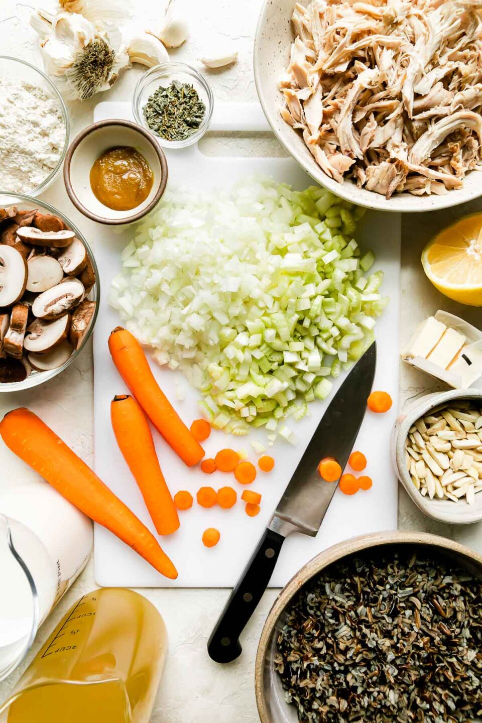 Slow Cooker Chicken Wild Rice Soup — Creamy Minnesota-Style Comfort in a Bowl 27 Overhead flat-lay of raw ingredients for slow cooker chicken wild rice soup — diced carrots, celery, onion, wild rice in a small bowl, raw chicken breasts, garlic cloves, and fresh thyme arranged on a light marble surface