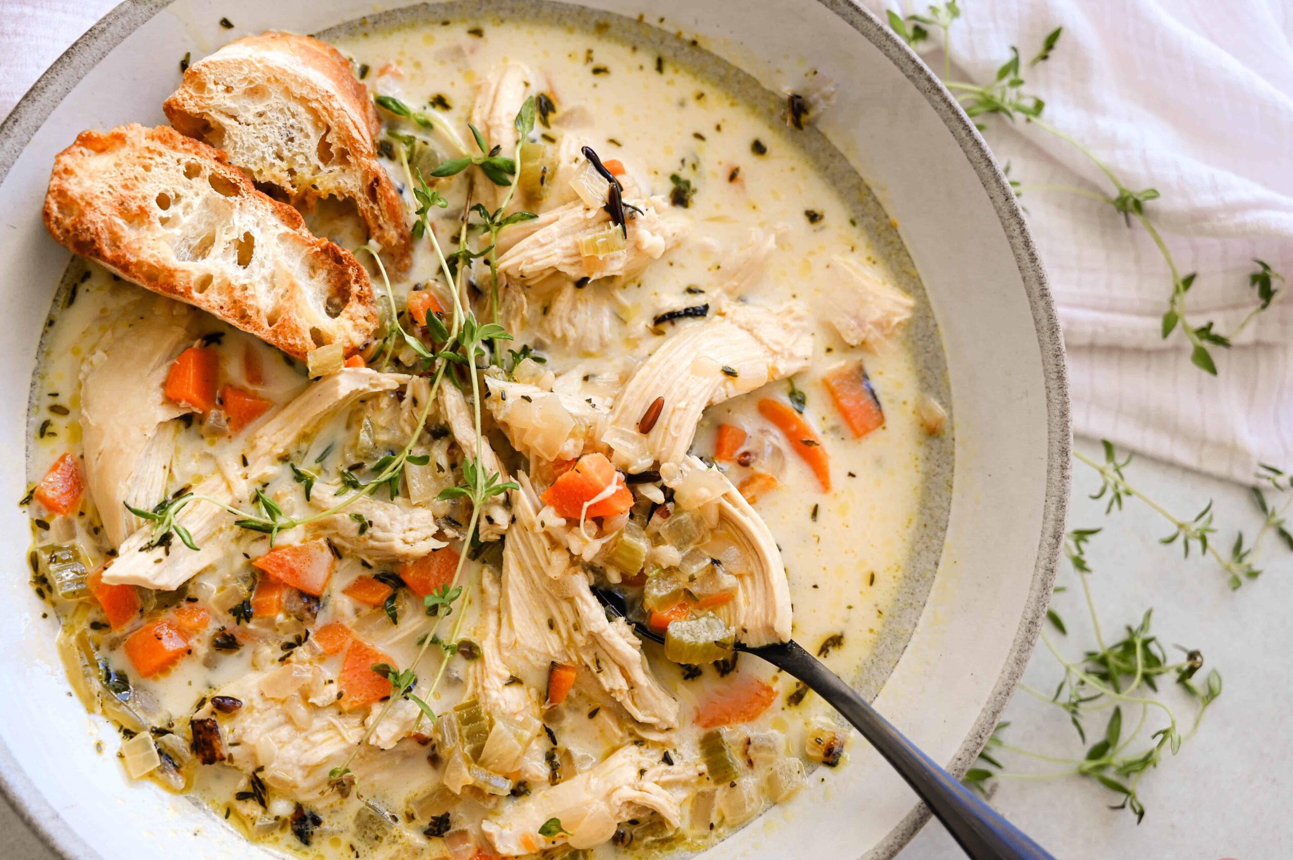 Slow Cooker Chicken Wild Rice Soup — Creamy Minnesota-Style Comfort in a Bowl 28 Close-up of a ladle lifting a generous scoop of creamy chicken wild rice soup from a slow cooker, showing the shredded chicken, plump wild rice grains, and colorful carrot and celery pieces in a velvety broth