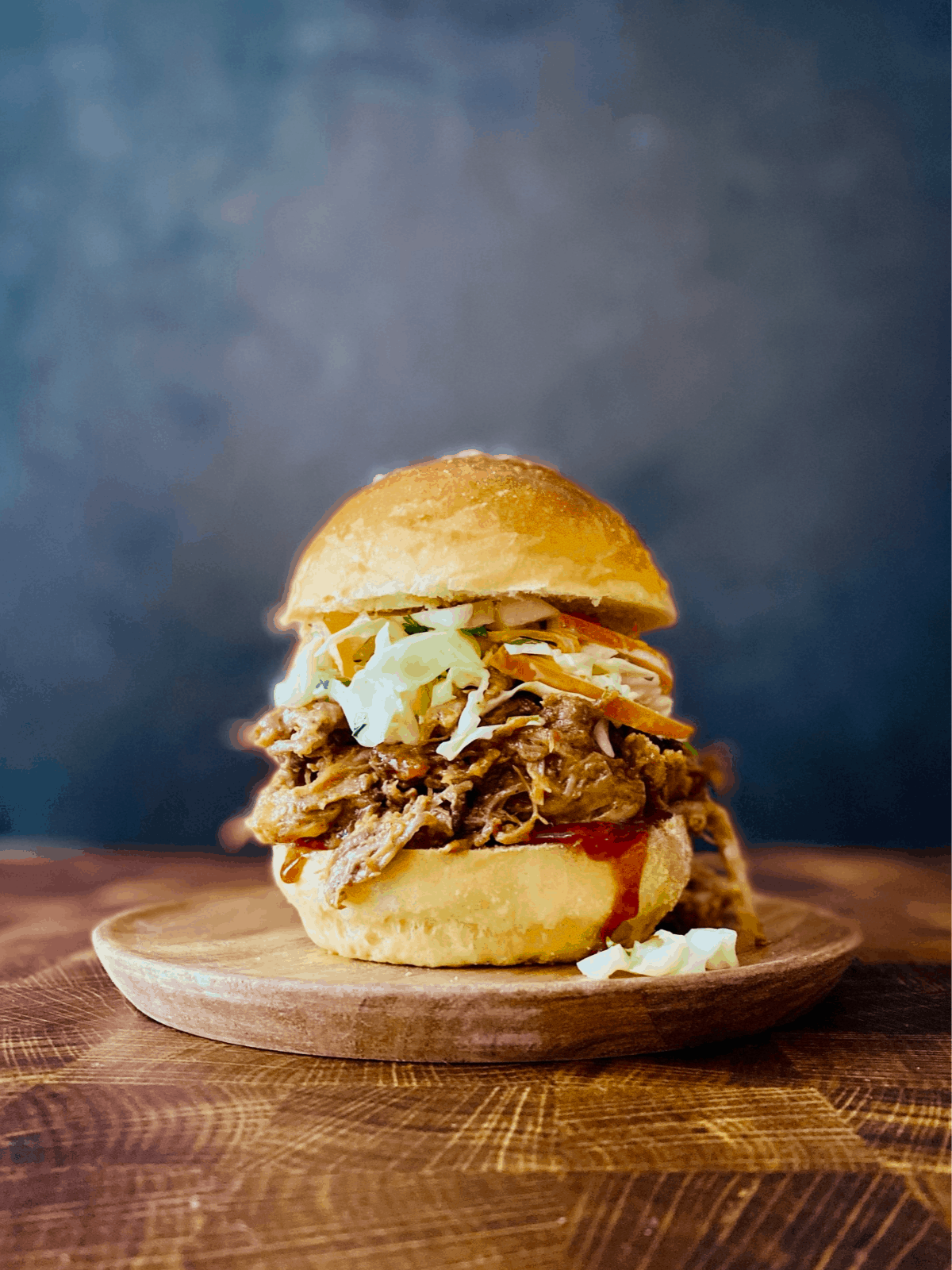 Slow cooker pulled pork served on a toasted bun with coleslaw and pickles, beautifully plated on a rustic wooden board