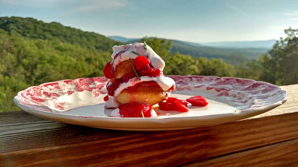 Strawberry Shortcake — The Classic Whipped Cream & Biscuit Dessert Worth Every Bite 28 Close-up shot of a single strawberry shortcake split open and layered with glistening macerated strawberries and billowing whipped cream, with a silver spoon beside it on a linen napkin