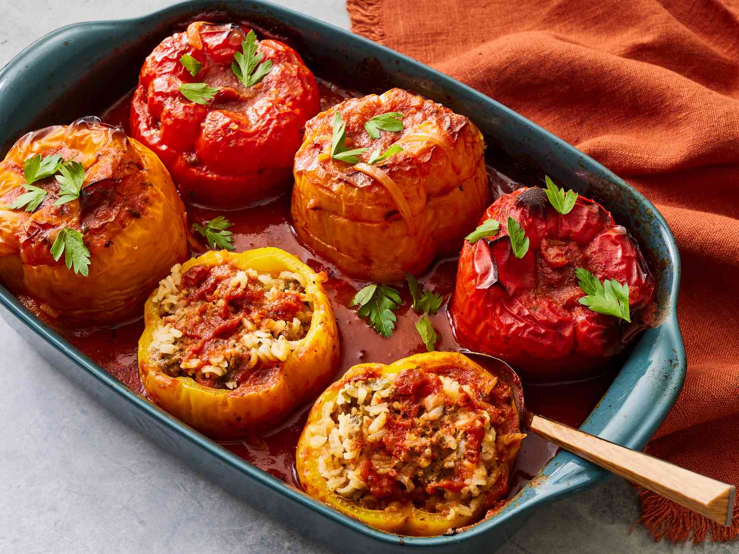 Overhead flat-lay of stuffed bell pepper ingredients including raw ground beef, halved bell peppers, cooked rice, shredded cheese, canned tomatoes, diced onion, and garlic on a wooden surface