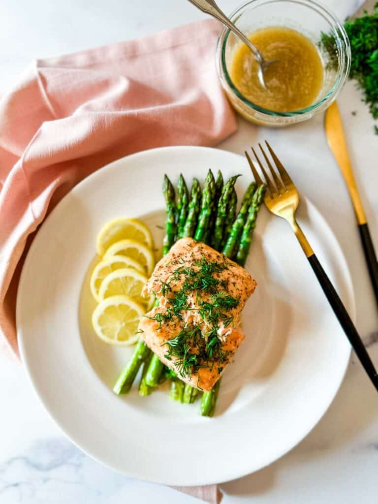 Air Fryer Salmon — Perfectly Flaky, Juicy, and Ready in 12 Minutes 26 Air fryer salmon fillets plated beautifully on a white dish with lemon slices, fresh dill, and a side of roasted asparagus