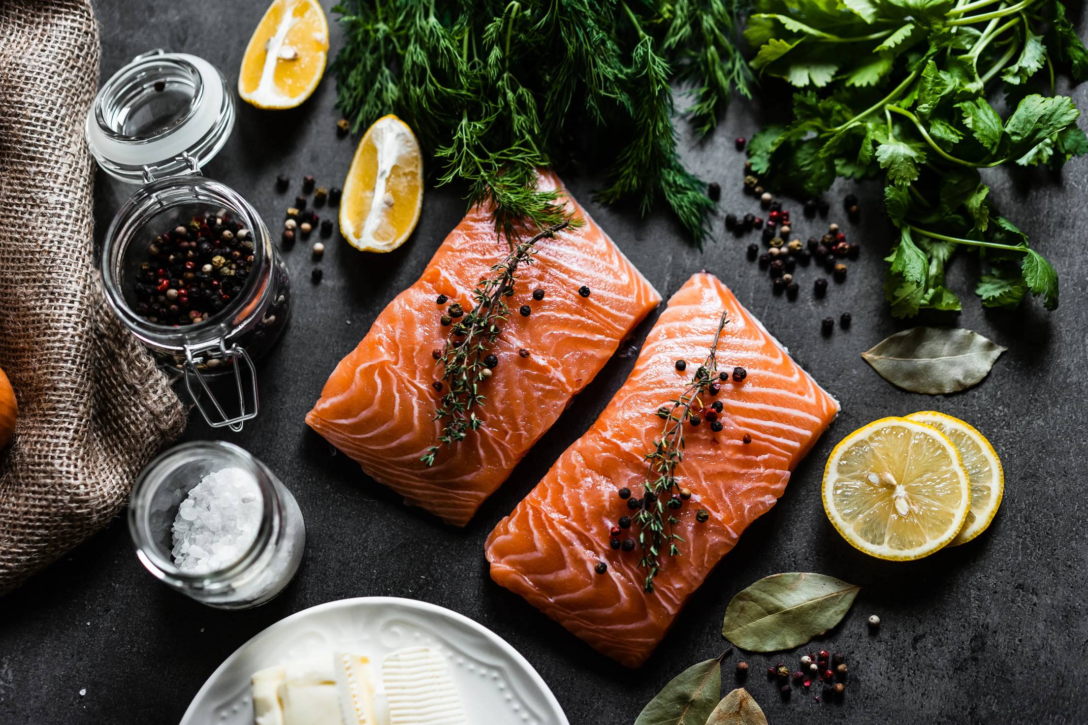 Air Fryer Salmon — Perfectly Flaky, Juicy, and Ready in 12 Minutes 27 Raw salmon fillets on a cutting board with olive oil, smoked paprika, garlic powder, lemon, salt, and fresh dill arranged around them as a flat lay ingredients shot