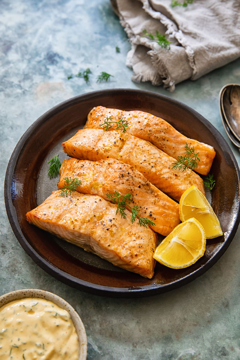 Air Fryer Salmon — Perfectly Flaky, Juicy, and Ready in 12 Minutes 28 Close-up of a perfectly flaked air fryer salmon fillet showing the tender, moist interior with a lightly crisped golden edge, garnished with fresh dill and lemon wedges